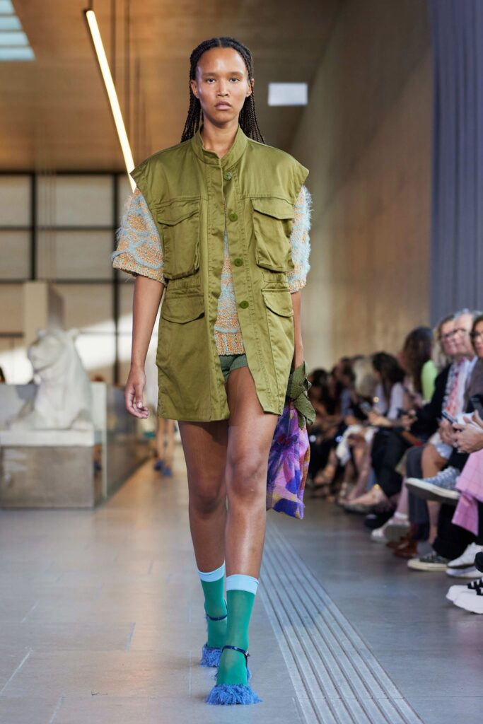 An oversized green jacket paired with multicolor shorts, showcasing a relaxed and stylish look.