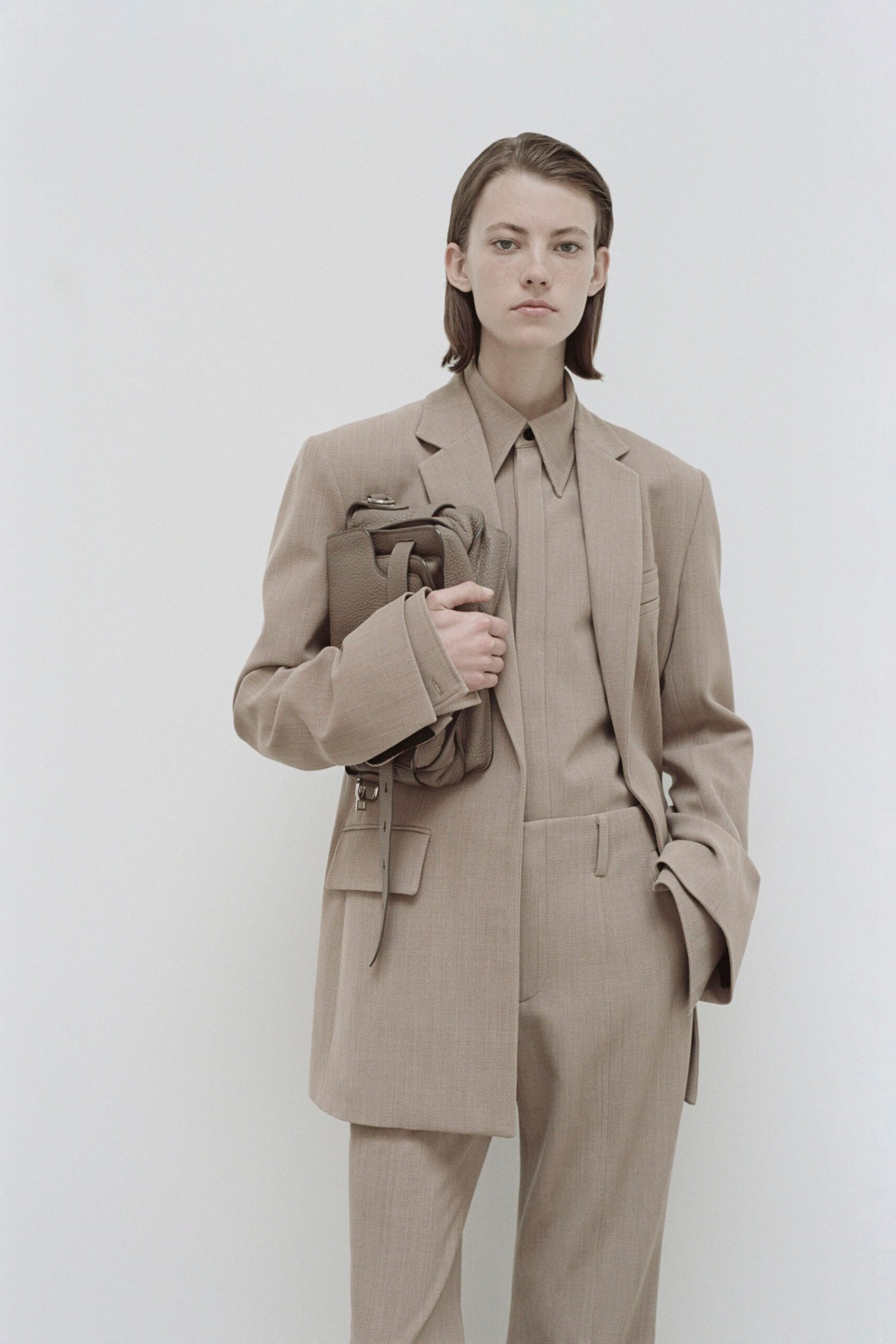 A tailored beige suit with a collared long-sleeve shirt and buttoned details.