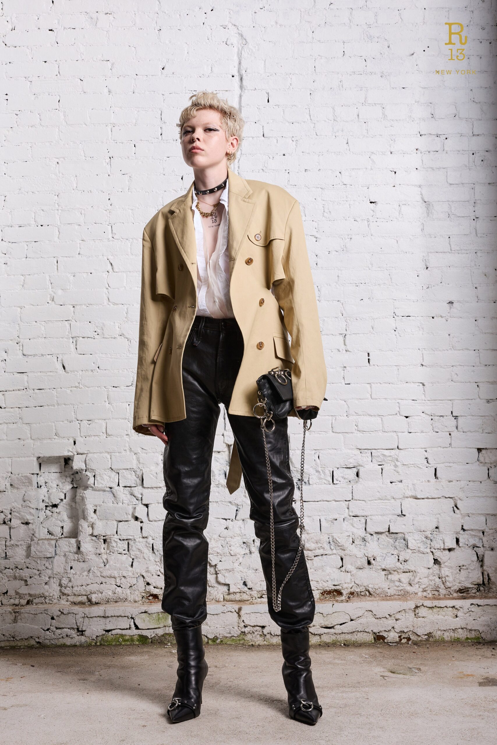 A fitted beige leather jacket with long sleeves paired with fitted black leather pants.