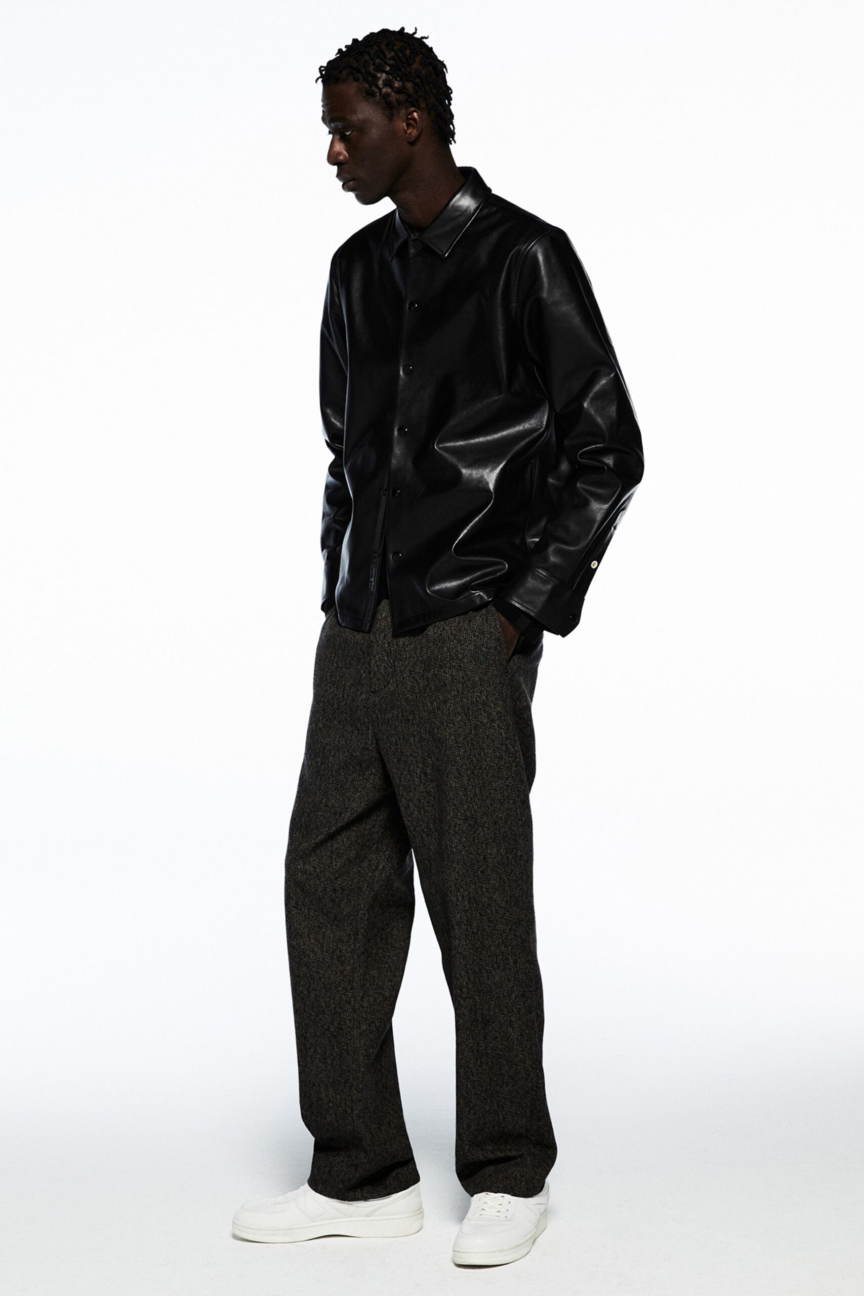 A relaxed black leather jacket with long sleeves paired with gray wool straight-leg pants.