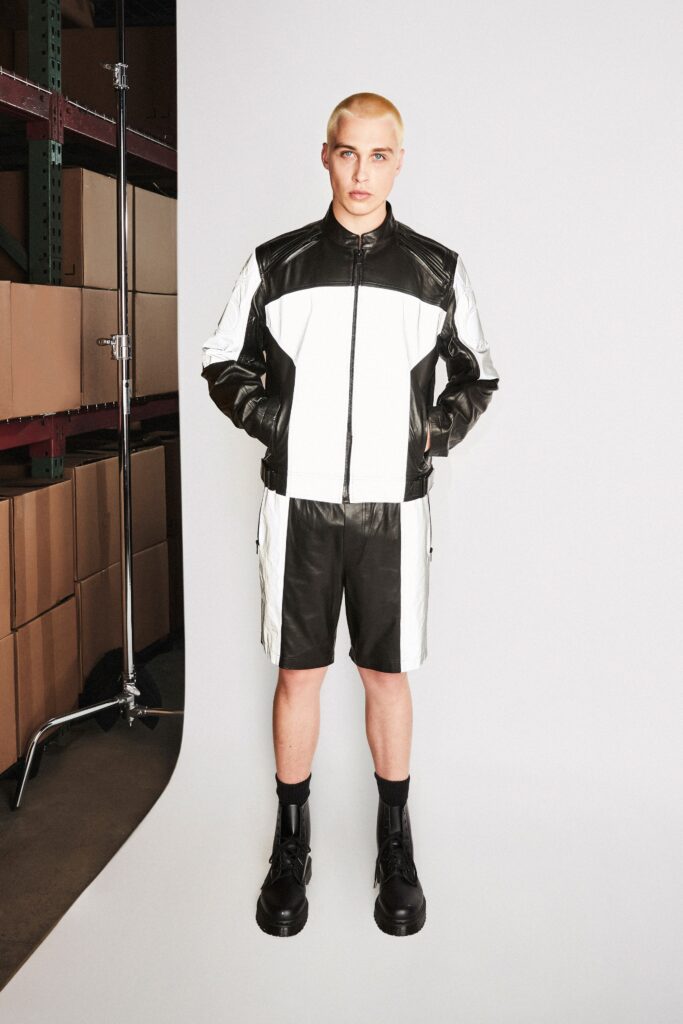 A fitted black and white leather jacket paired with matching shorts featuring a color-blocked design.