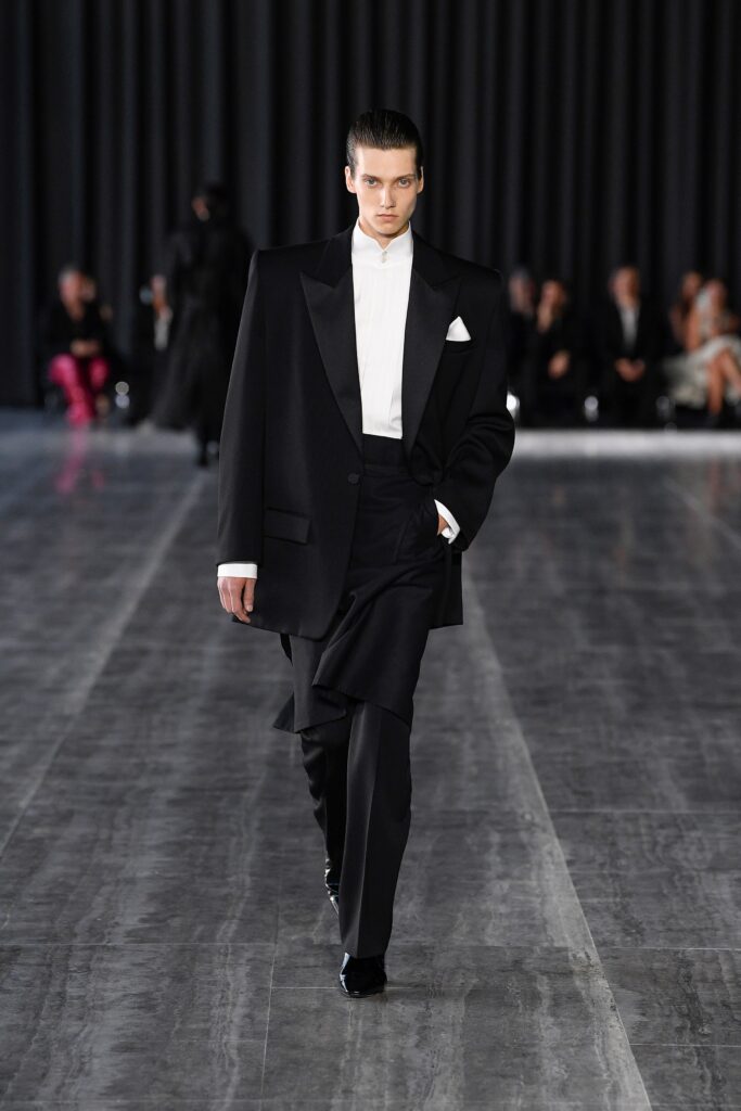 An oversized black wool suit with long sleeves and a collared design, featuring buttoned details.