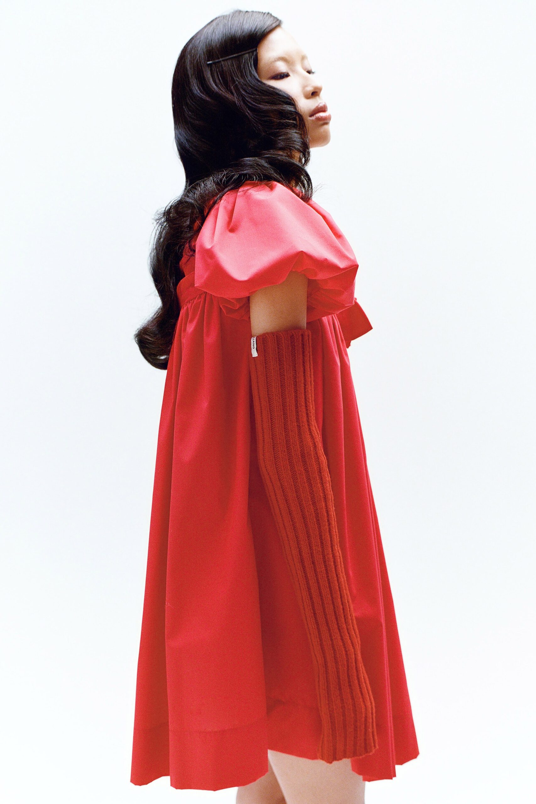 A relaxed red cotton dress with short sleeves and pleated details.