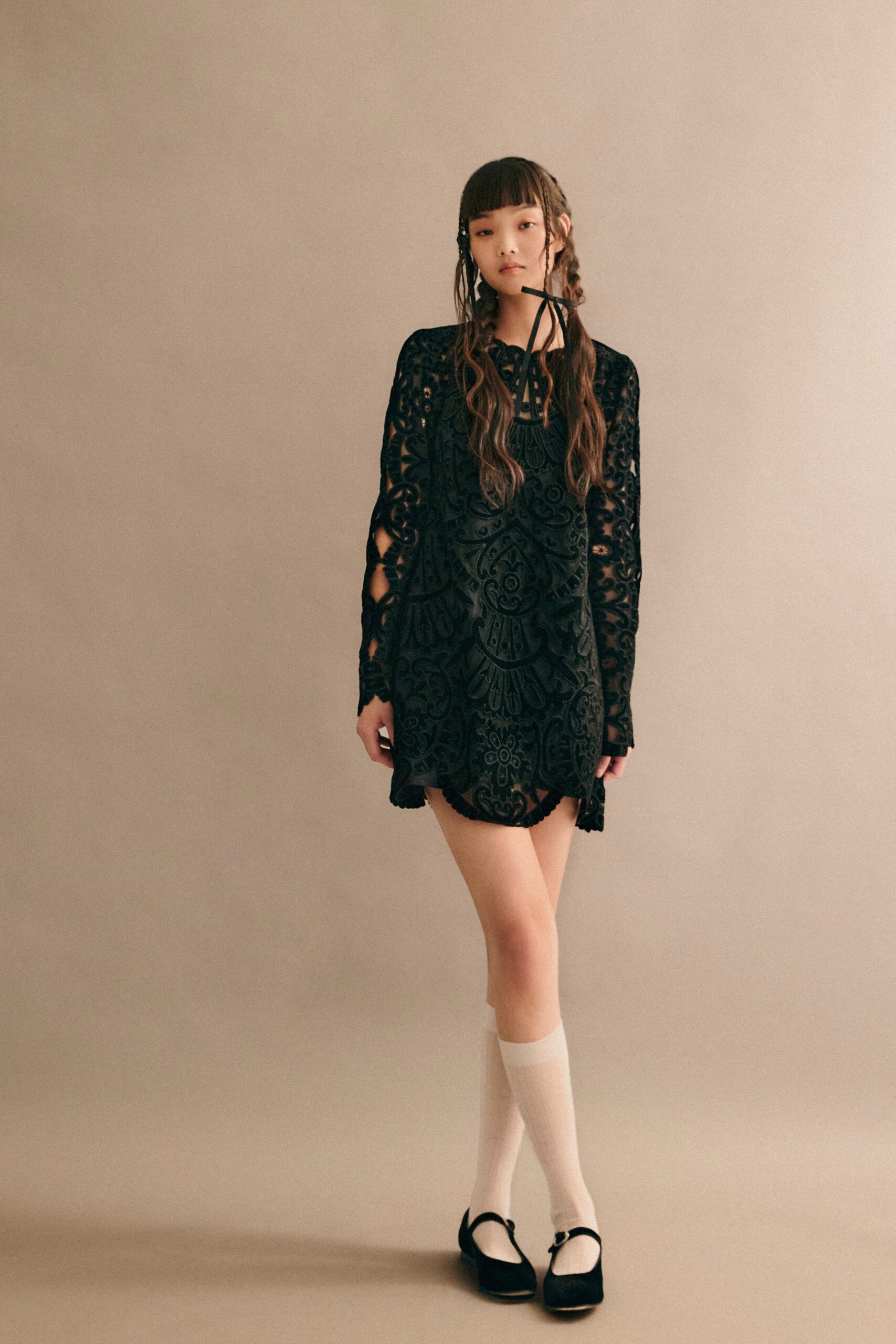 A fitted black lace long-sleeve dress with an embroidered design and mini length.