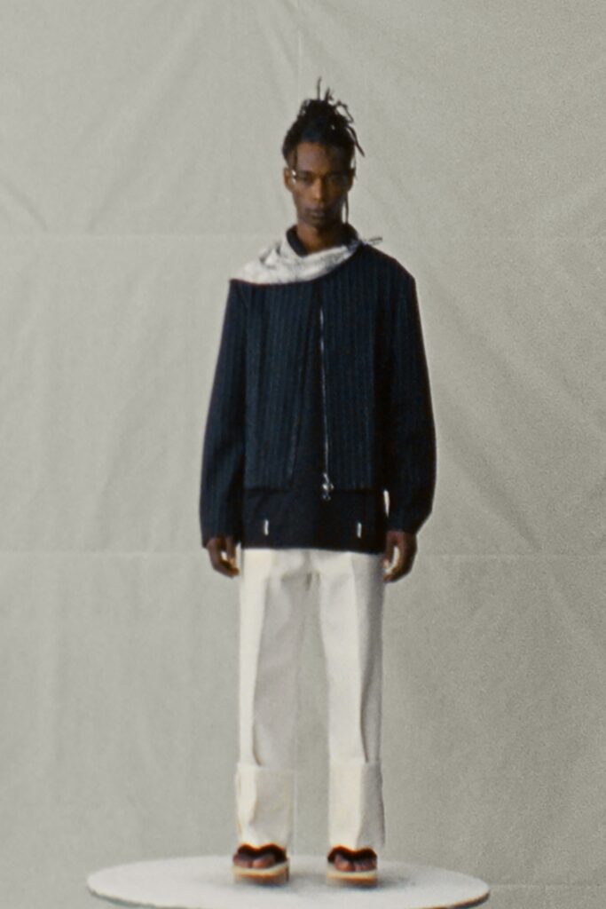 A relaxed black striped jacket paired with white pants, featuring a collared neckline.