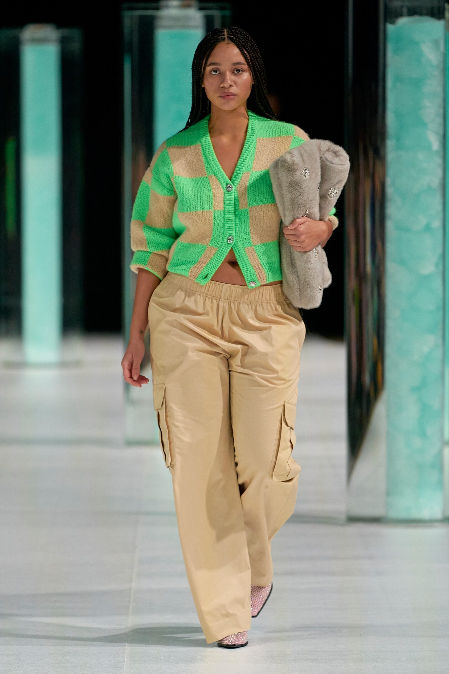 A relaxed green striped cardigan paired with beige pants for a stylish runway look.