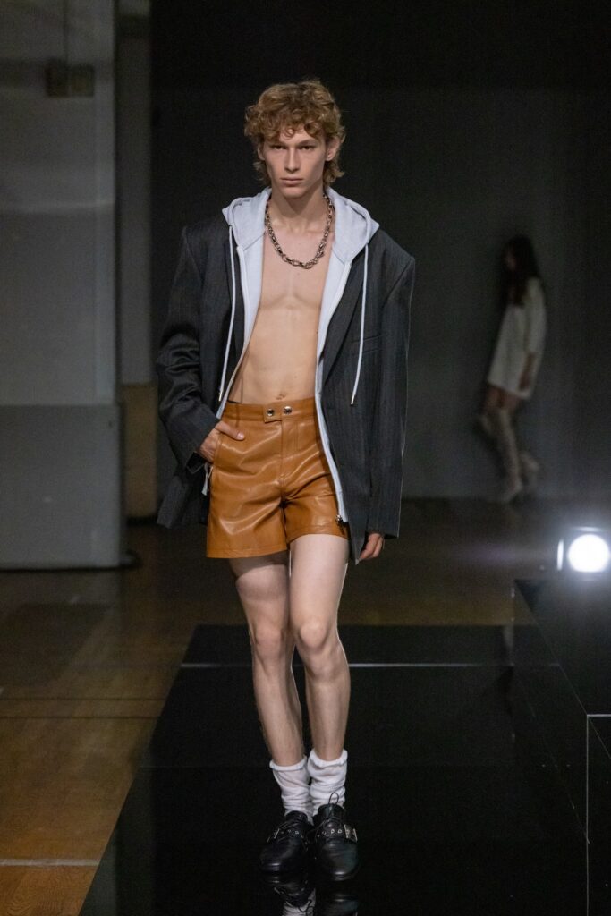 A fitted black jacket with a collared design paired with brown leather shorts.