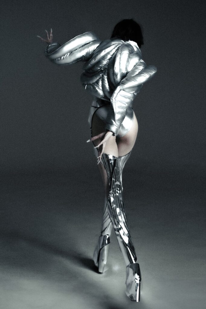 A fitted silver metallic jacket with long sleeves and high neck, paired with sleek pants.