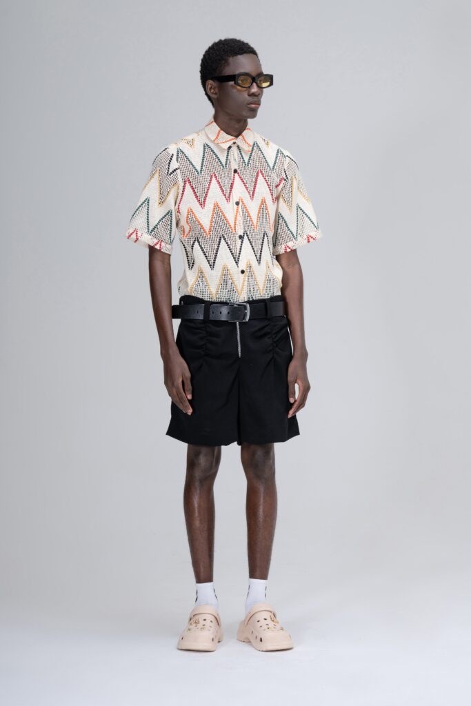 A relaxed-fit multicolor printed shirt with short sleeves paired with black shorts.