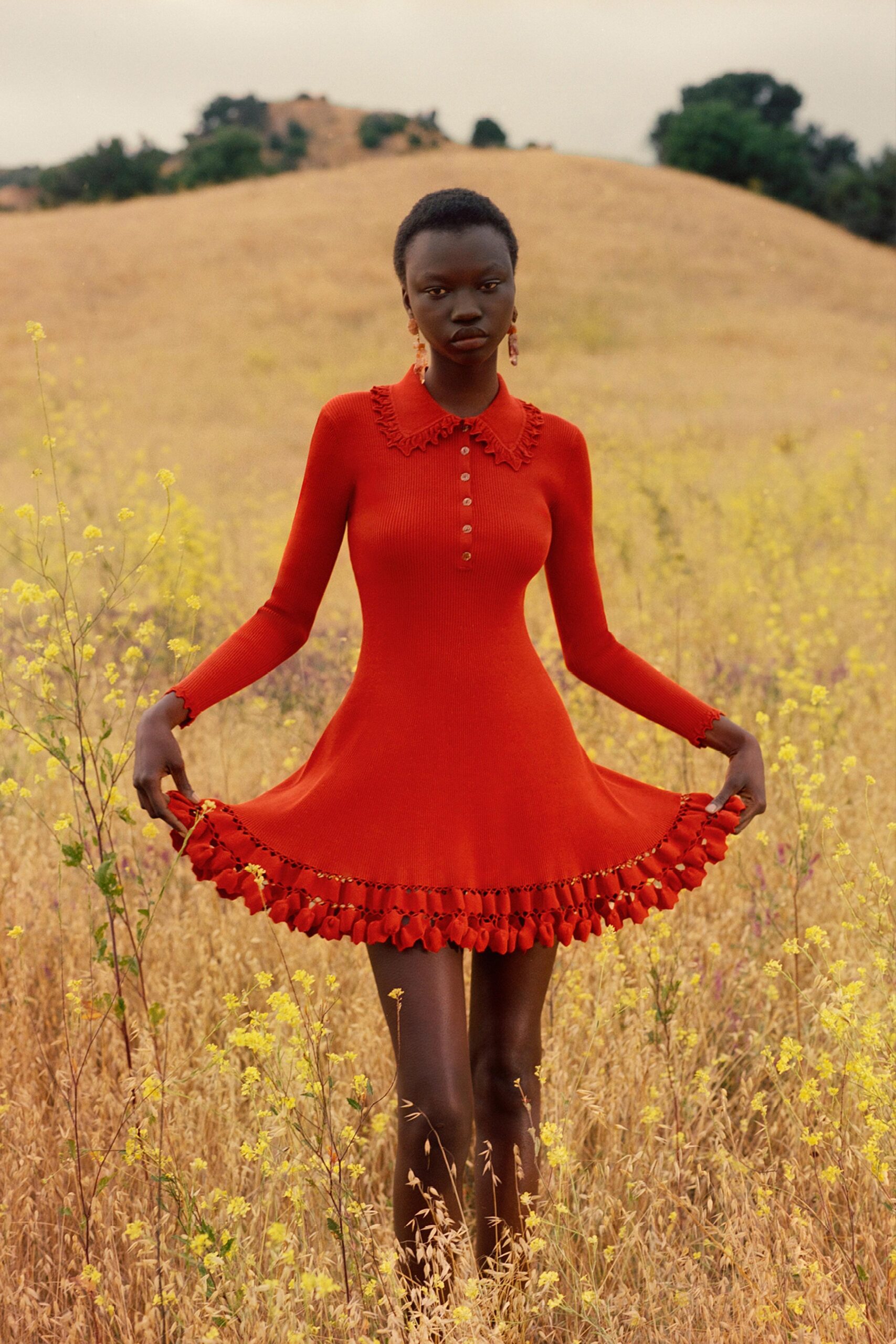A fitted red long-sleeve dress with a collared neckline and pleated tiered hem.
