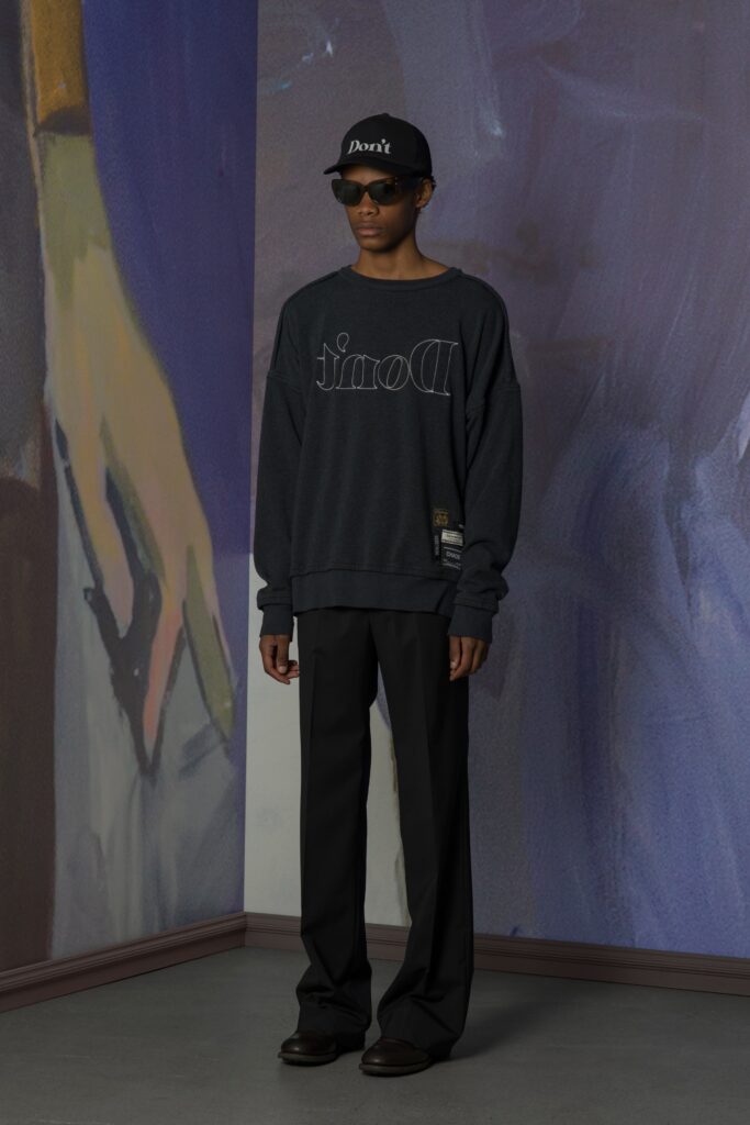 A relaxed black sweater with a printed design paired with black pants.
