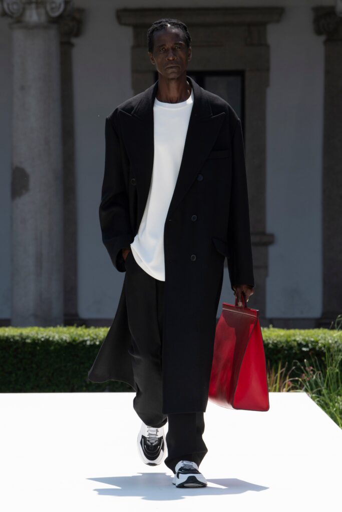 A relaxed black coat over a white shirt paired with black pants.