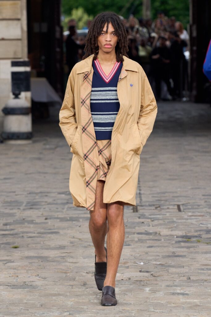 A relaxed beige coat paired with blue striped shorts featuring a checkered design.