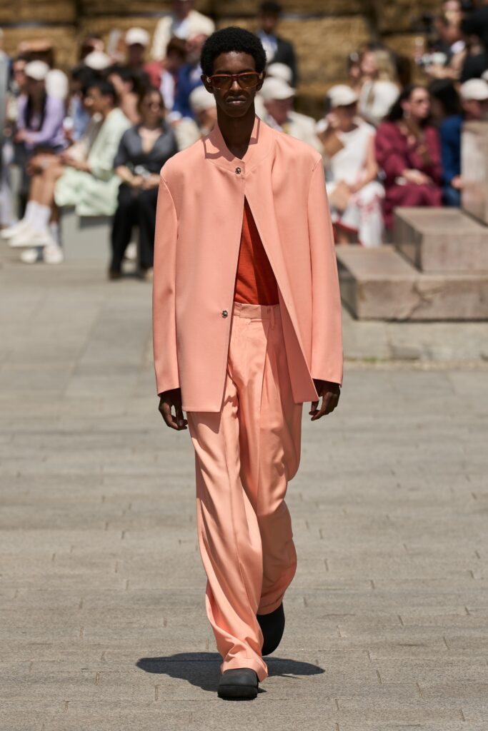 A relaxed pink jacket with long sleeves and collared design paired with straight-leg pants.