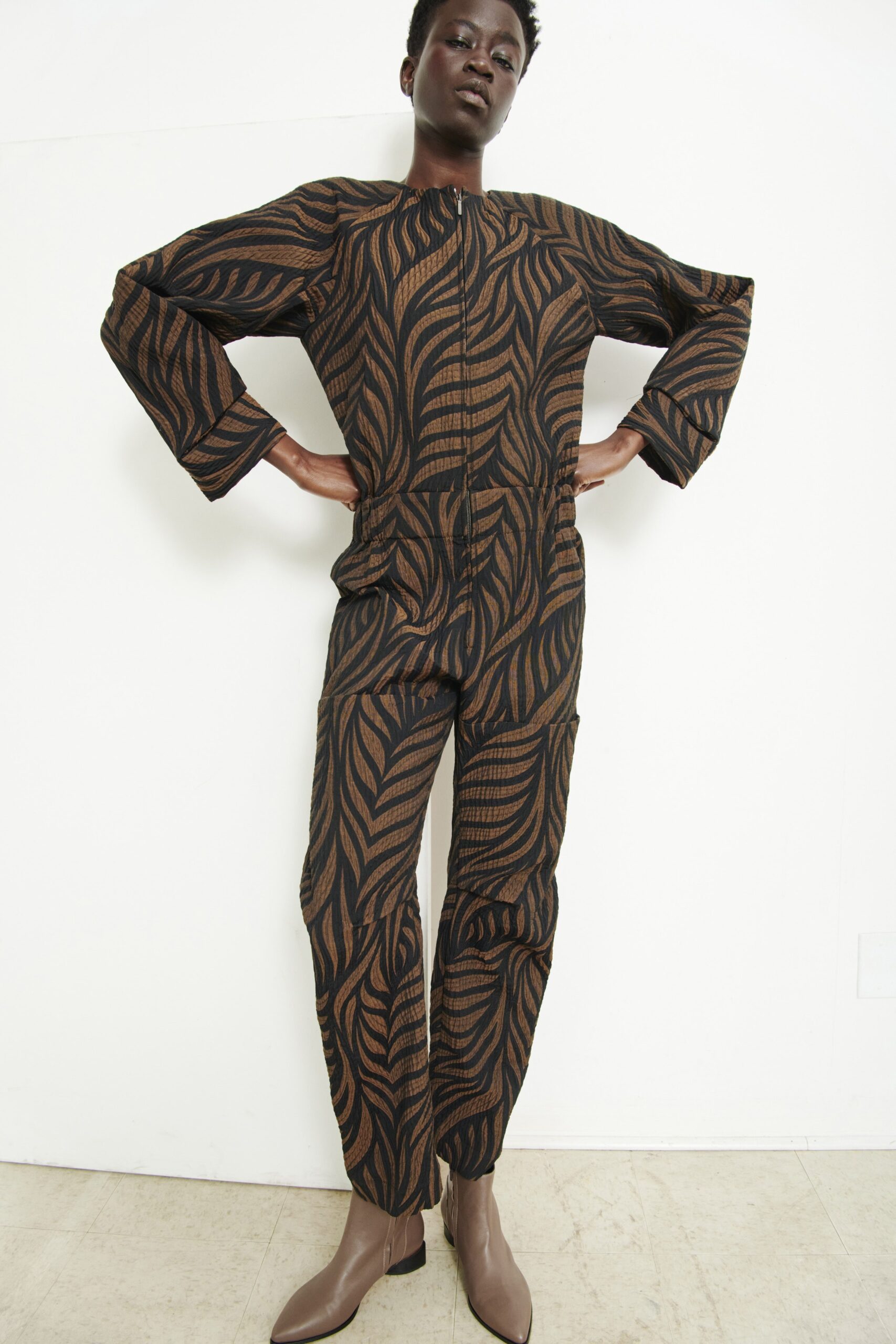 A relaxed black and brown printed jumpsuit with long sleeves and a collared neckline.