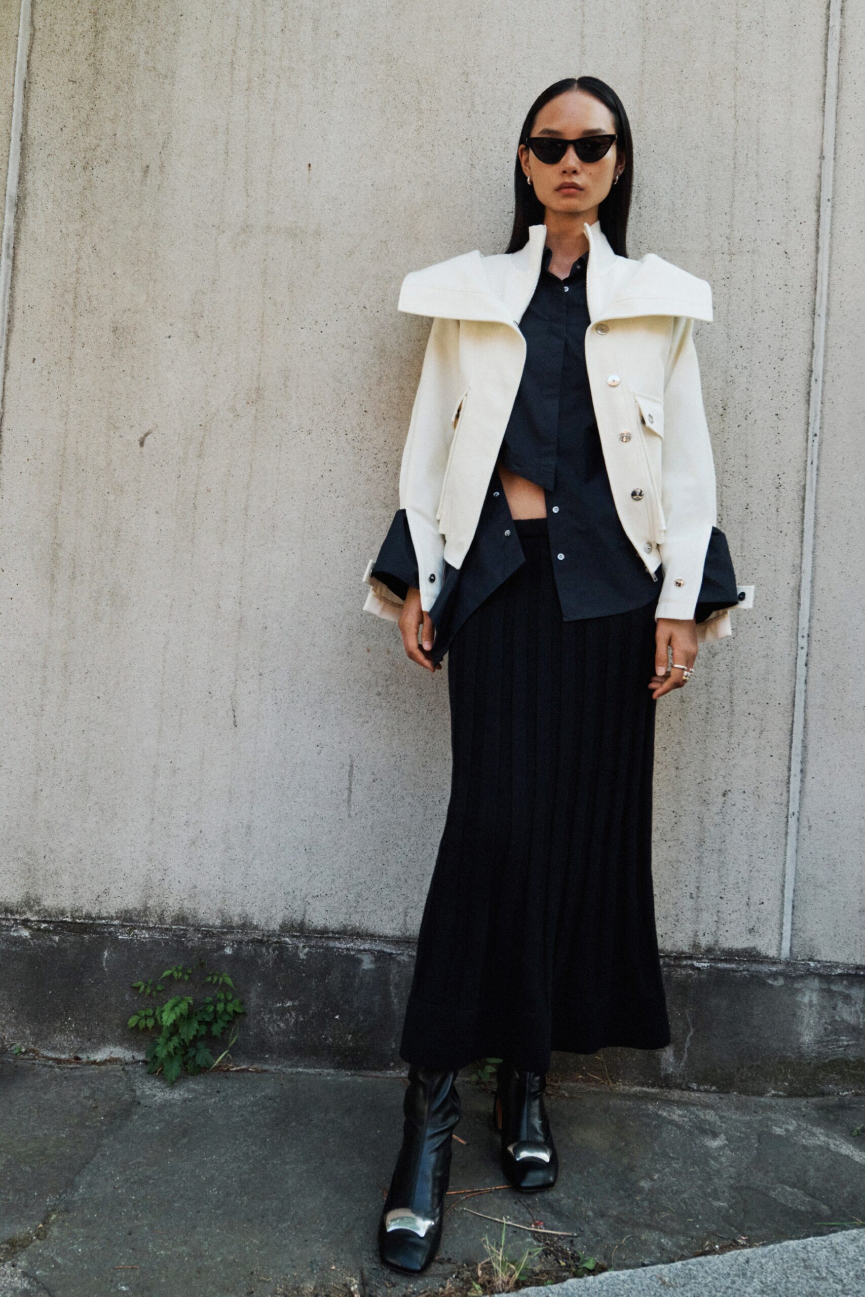 A fitted black pleated skirt paired with a stylish white collared coat.