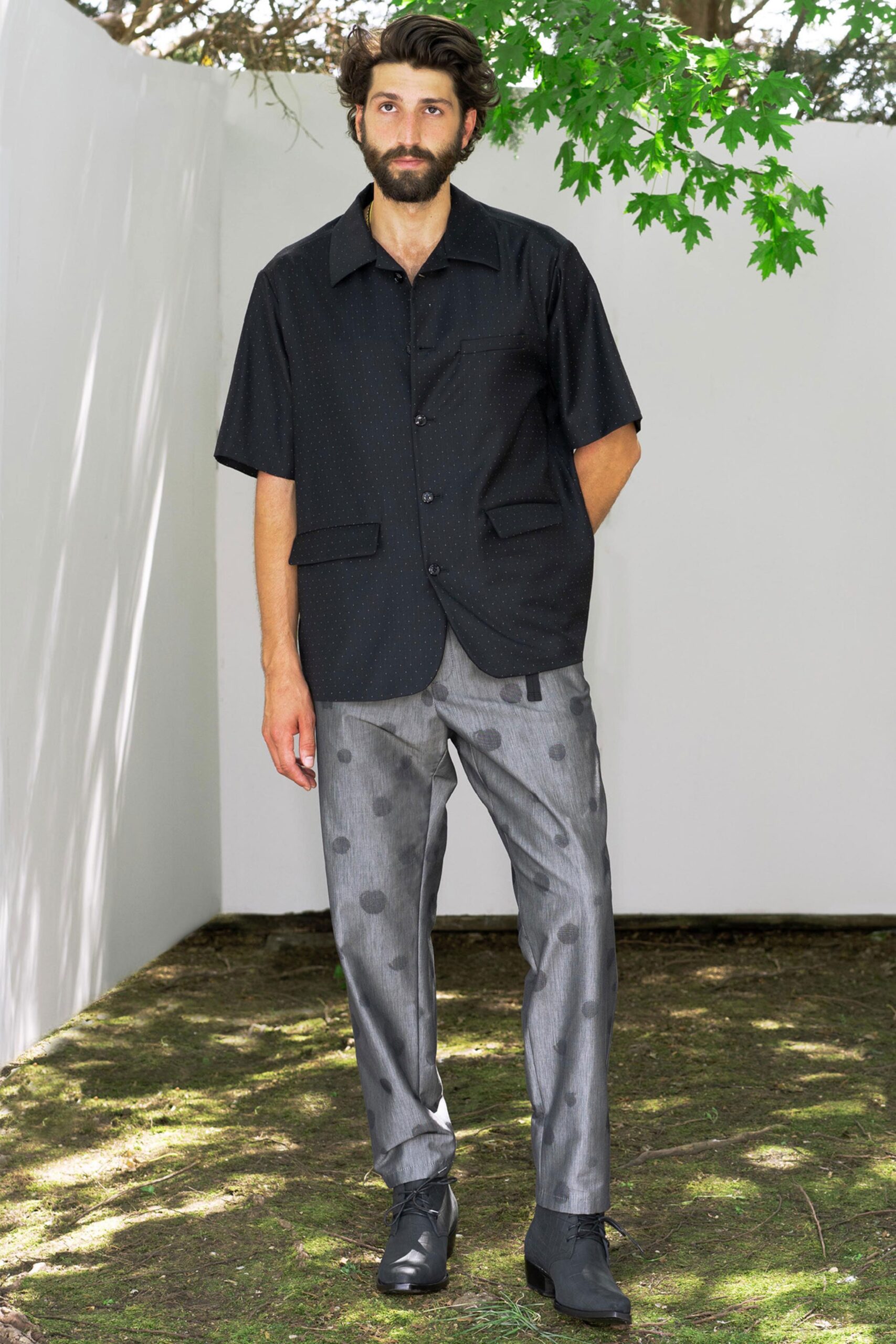 A relaxed black short-sleeve collared shirt paired with printed gray straight-leg pants.