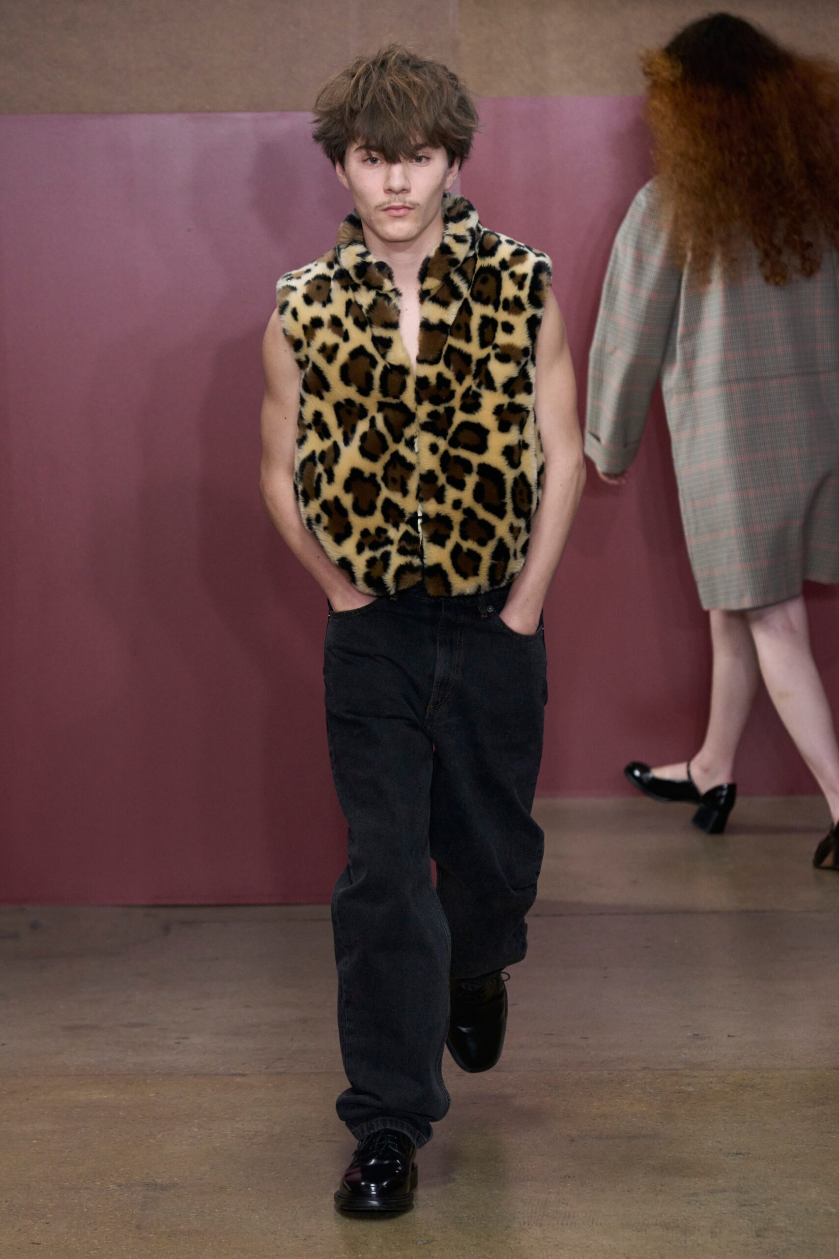 A relaxed-fit brown animal-print vest paired with straight-leg black denim pants.