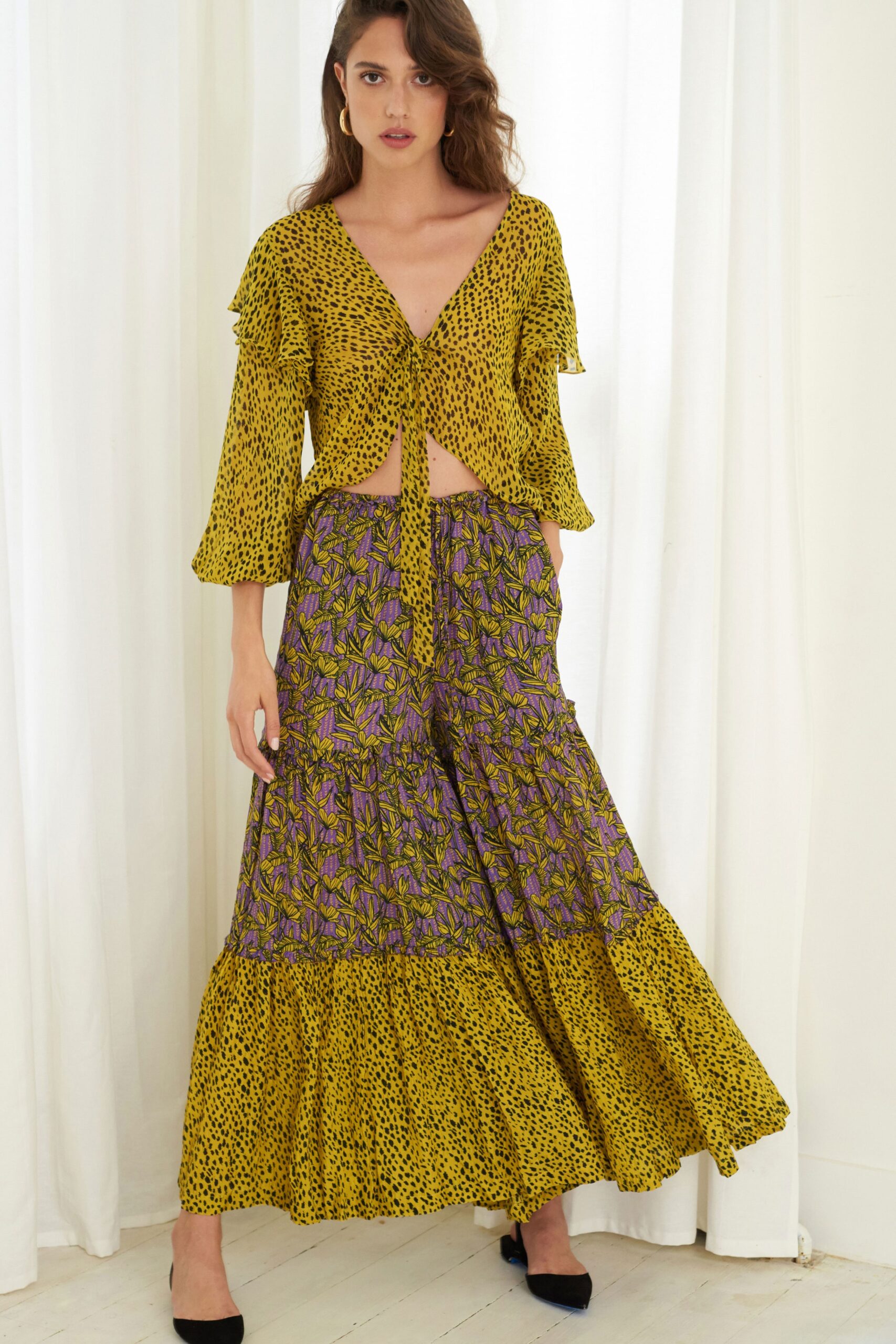 A relaxed yellow printed top with long sleeves paired with a flared skirt featuring purple accents.