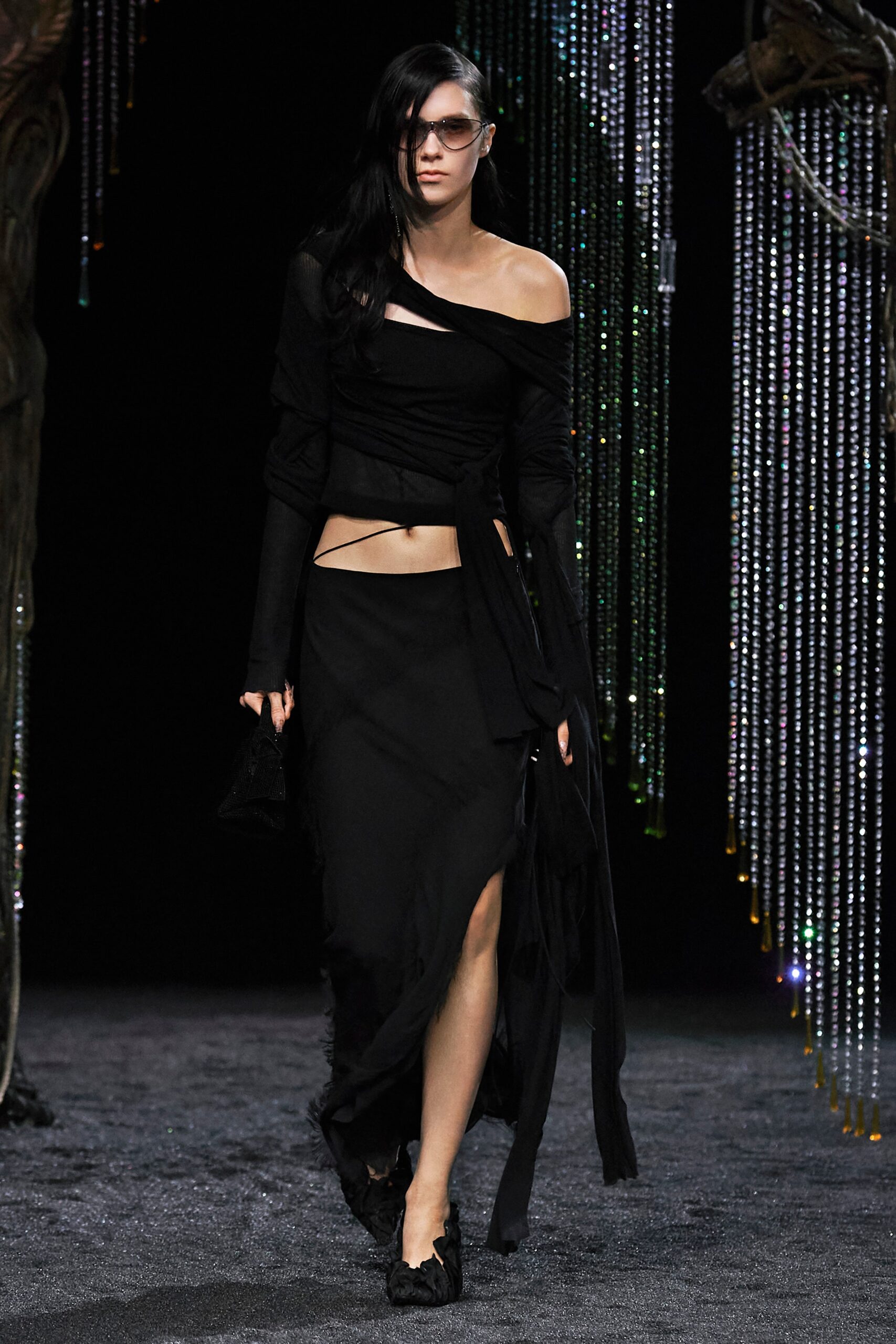 A fitted black silk dress with an off-shoulder design and asymmetric slit detail.