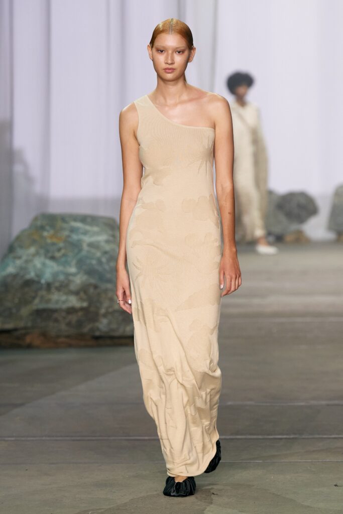 A fitted beige sleeveless dress with a high neckline and straight-leg silhouette.