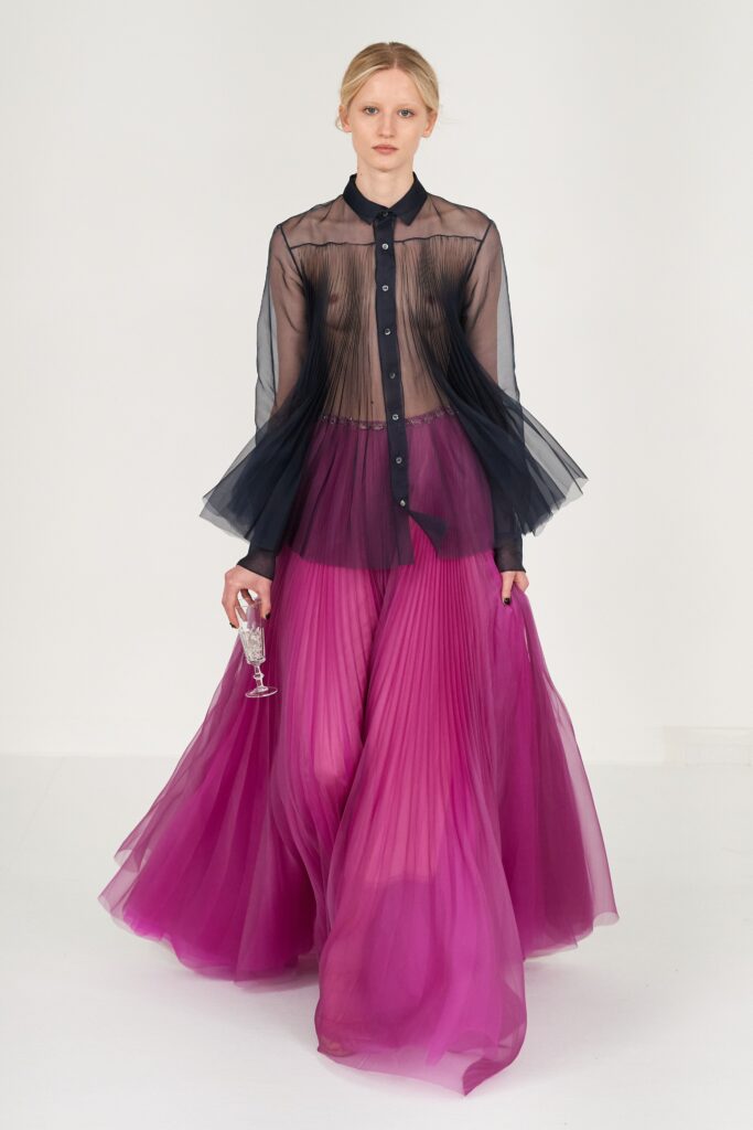 A fitted black and pink pleated dress with long sleeves and a collared neckline.