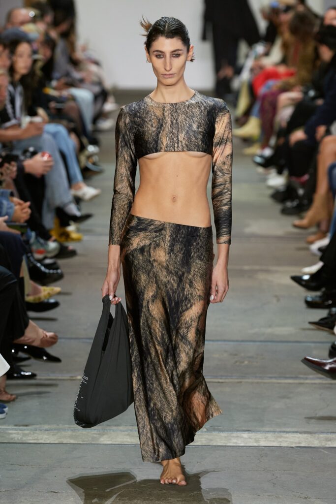 A fitted brown silk dress with long sleeves and an asymmetric design.