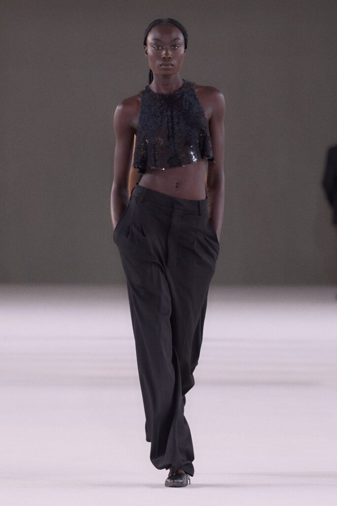 A relaxed black sequin sleeveless top paired with high-waisted straight-leg pants.