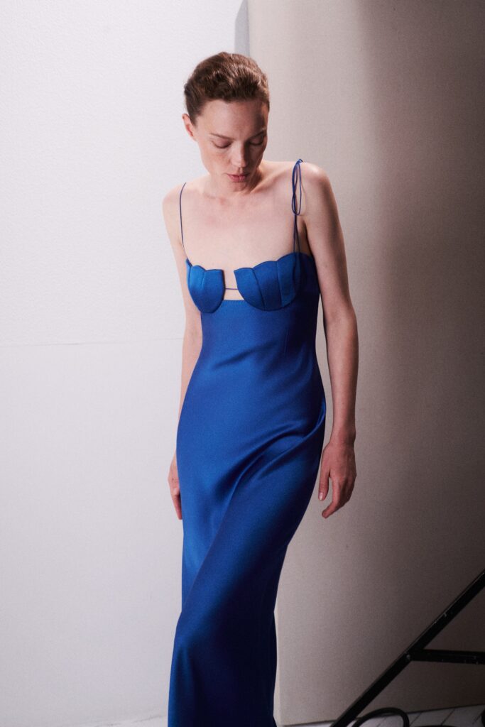 A fitted blue silk dress with a sleeveless design and a V-neckline featuring a slit detail.