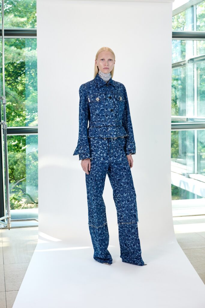 A fitted blue denim jacket with long sleeves and a collared neckline, paired with flared pants featuring a printed design.