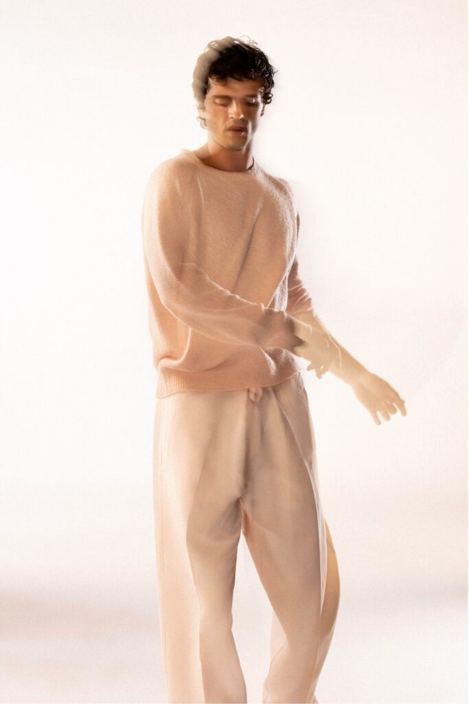 A relaxed pink long-sleeve sweater paired with beige straight-leg pants.