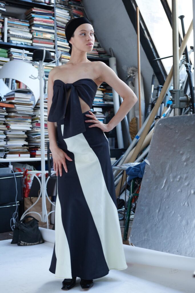 A fitted black and white asymmetric dress with a strapless design and a unique bow detail.