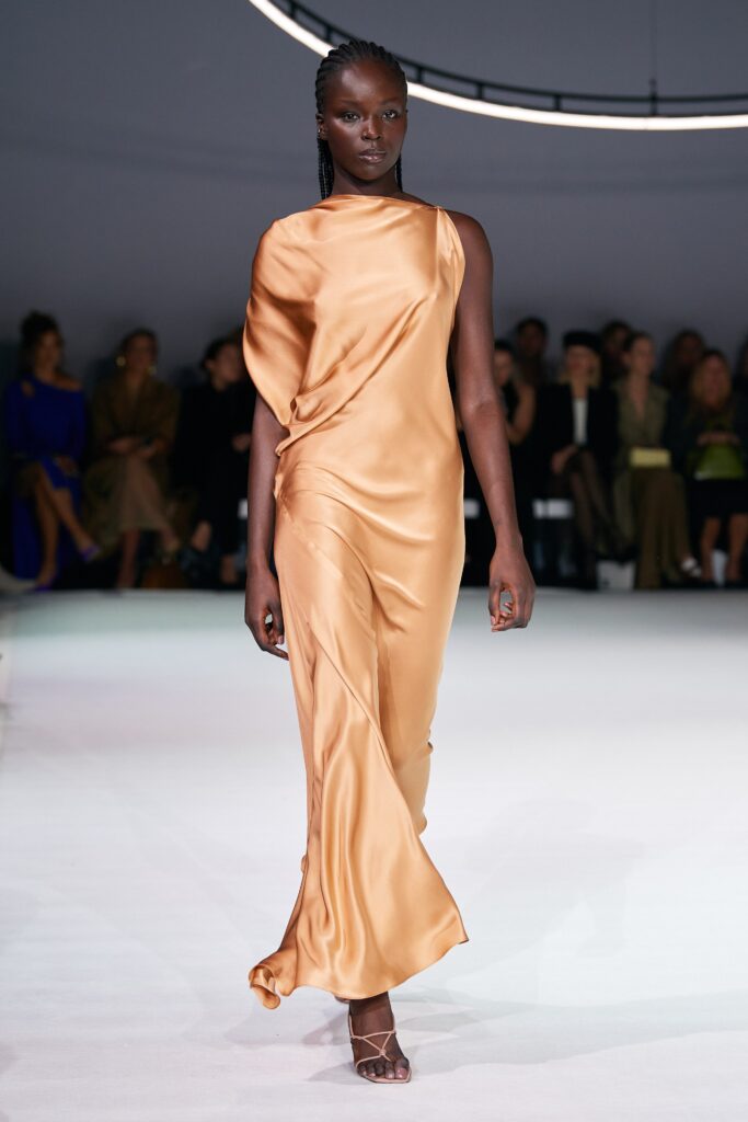 A fitted orange silk dress with a sleeveless design and draped detailing.