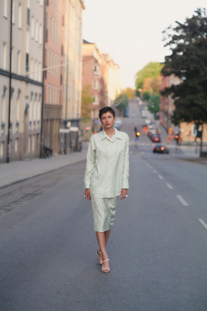 A fitted green silk dress with long sleeves and a collared neckline.