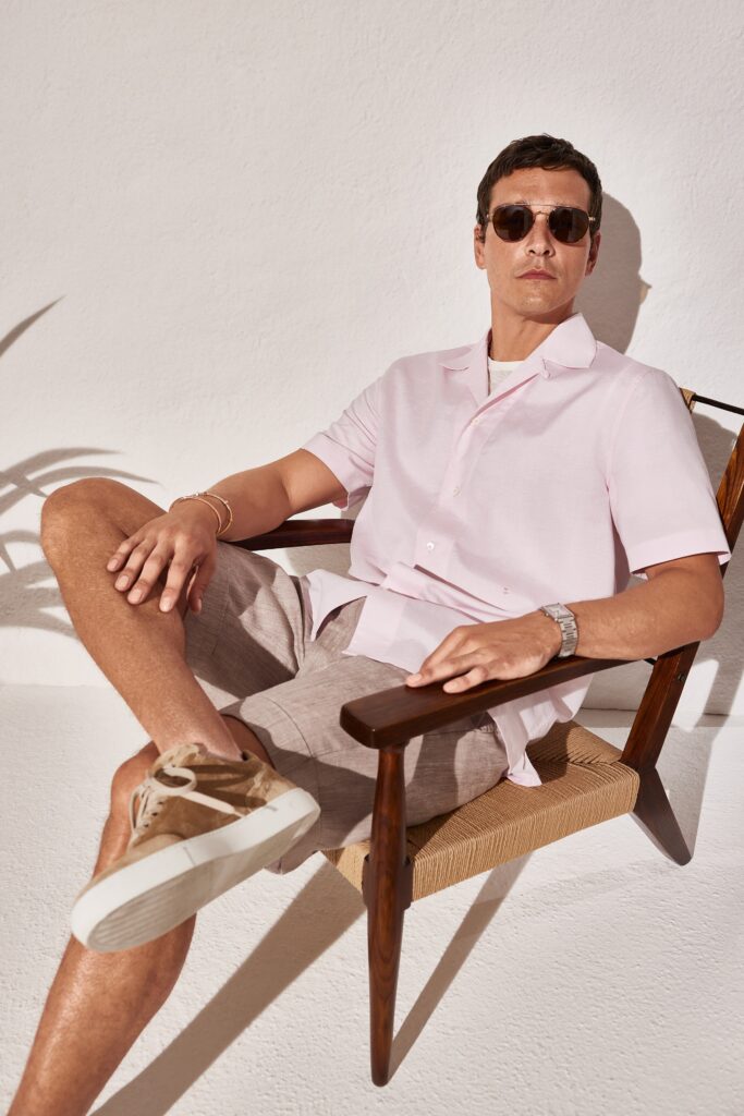 A relaxed pink cotton short-sleeve shirt paired with beige shorts, perfect for casual summer wear.