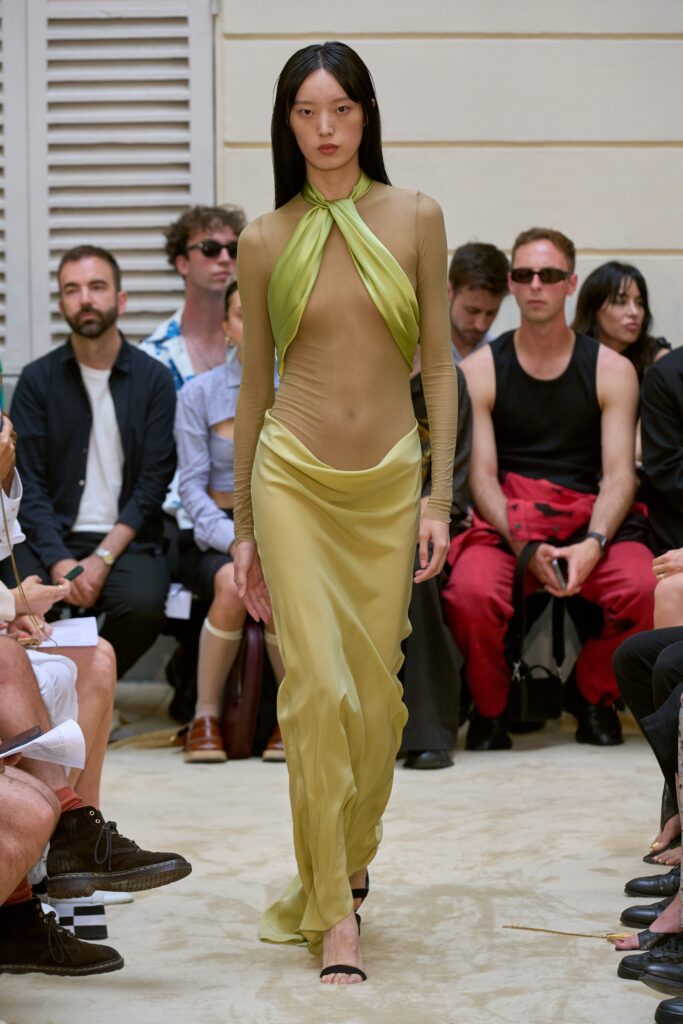 A fitted green silk dress with a sleeveless design and asymmetric silhouette.