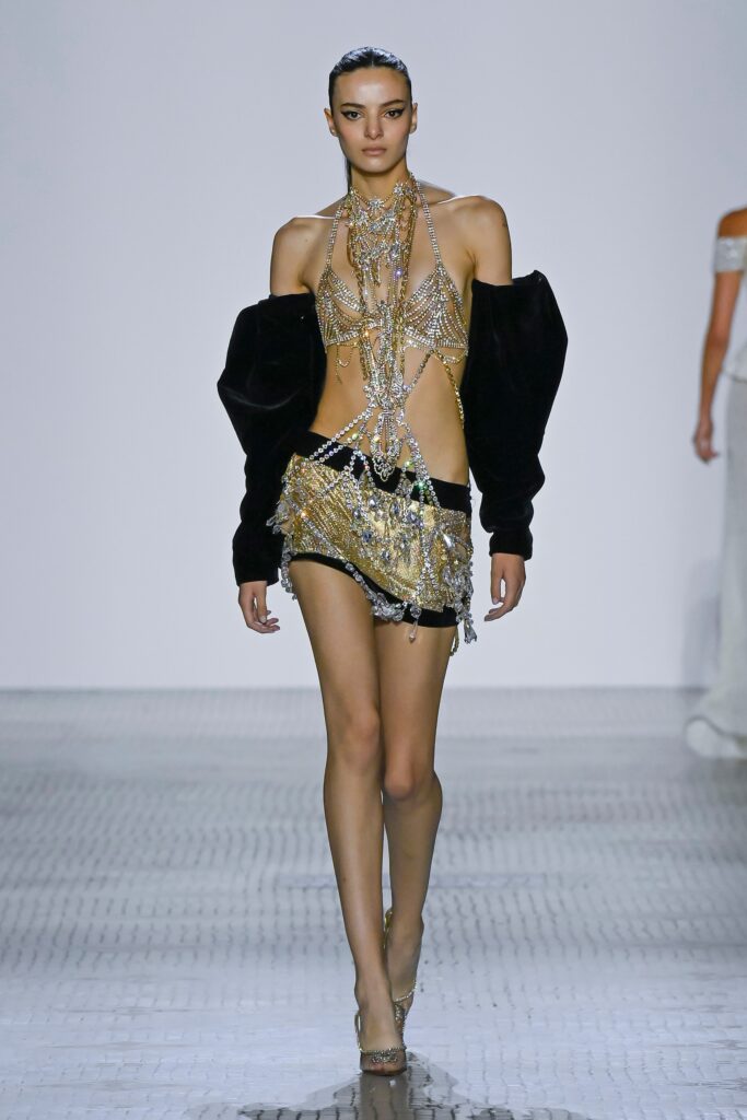 A fitted black silk sleeveless dress with a V-neckline and embellished details.