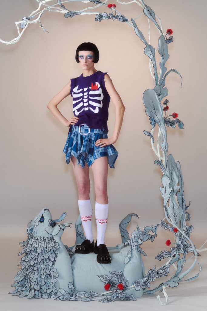 A fitted purple sleeveless top with a skeleton print paired with a blue asymmetric skirt.