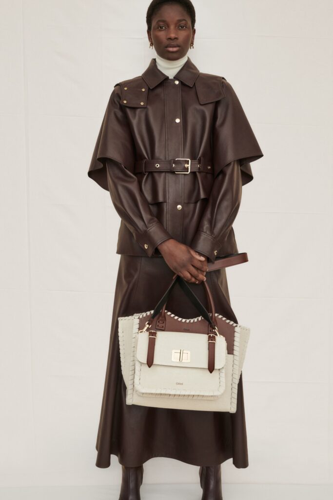 A fitted brown leather belted dress with long sleeves and a collared neckline in an A-line silhouette.