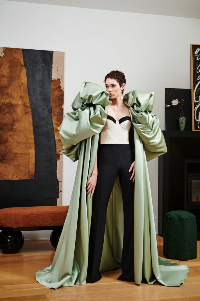 A fitted green silk coat with a layered design paired with black fitted pants.