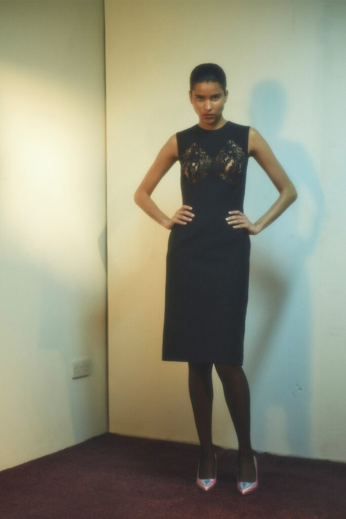 A fitted black silk dress with a sleeveless design and high-neck construction.
