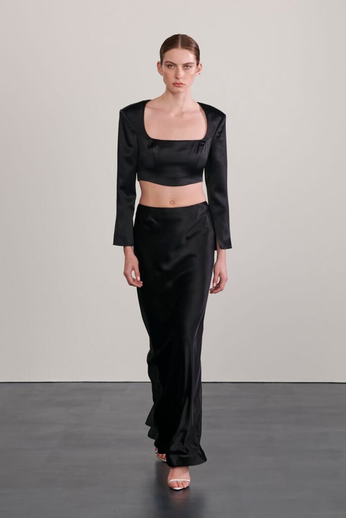 A fitted black silk dress with long sleeves and a square neckline, featuring a straight-leg silhouette.