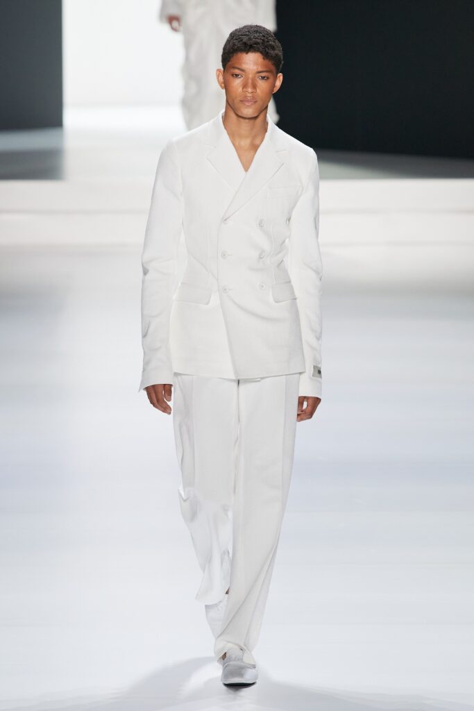 A tailored white suit featuring a long-sleeve collared jacket and buttoned details.