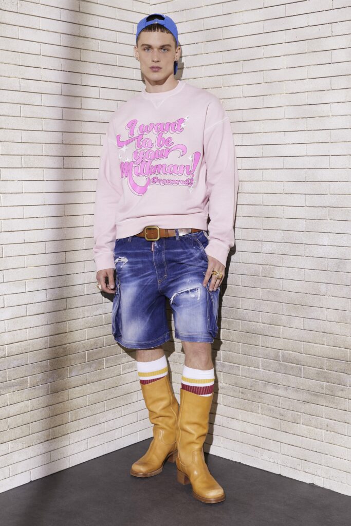 A relaxed pink printed sweater paired with high-waisted distressed denim shorts.