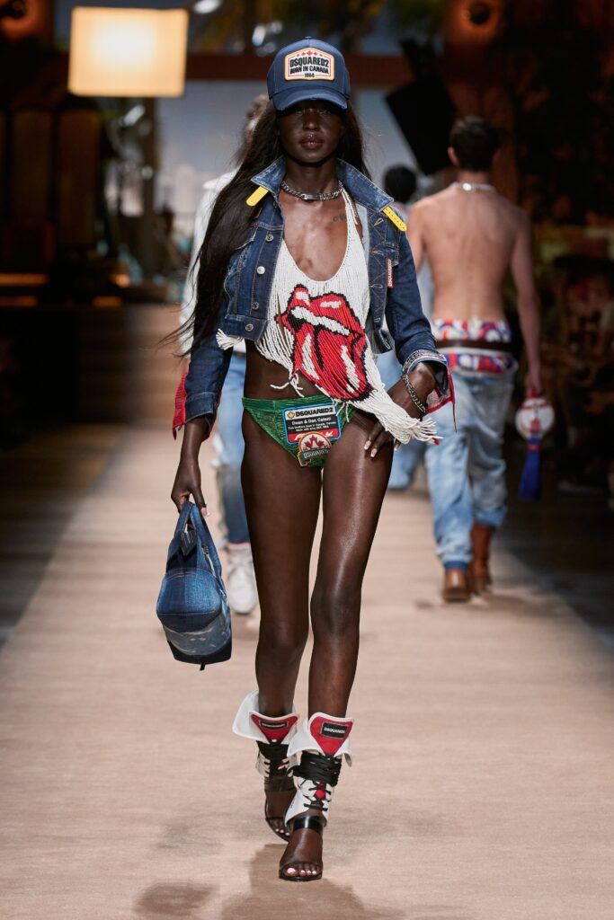 A fitted blue denim jacket with a fringed design and a printed top underneath.