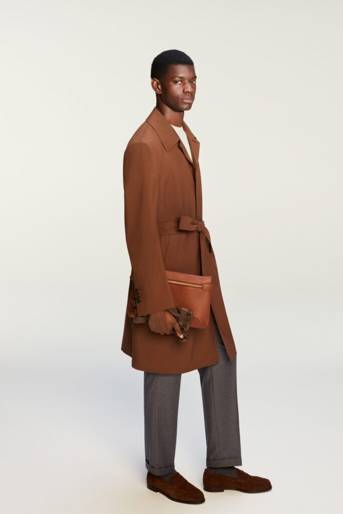 A tailored brown wool coat with a belted waist and long sleeves, paired with gray tailored pants.