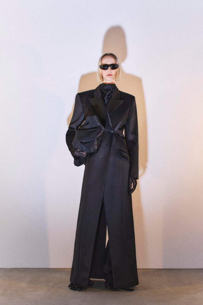 A fitted black leather coat with long sleeves and a collared design, paired with matching pants.