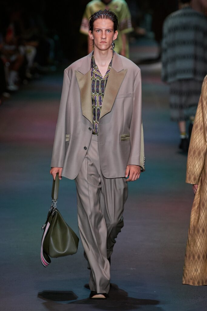 A tailored beige cotton suit with long sleeves and a collared shirt, featuring buttoned details.