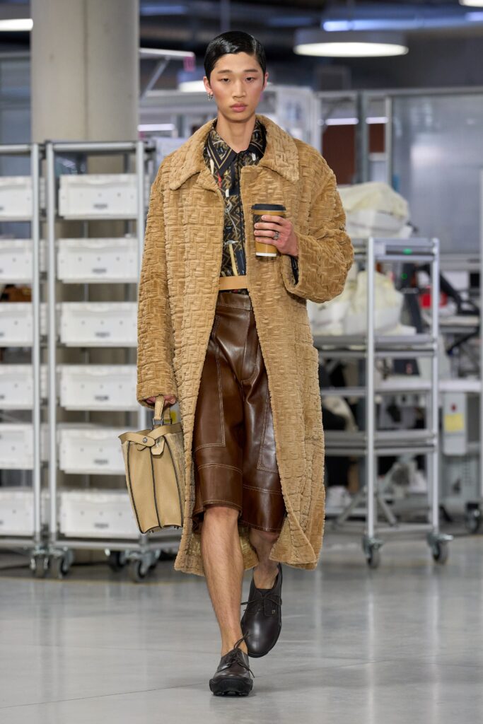 A fitted brown leather coat paired with a pleated asymmetric skirt.