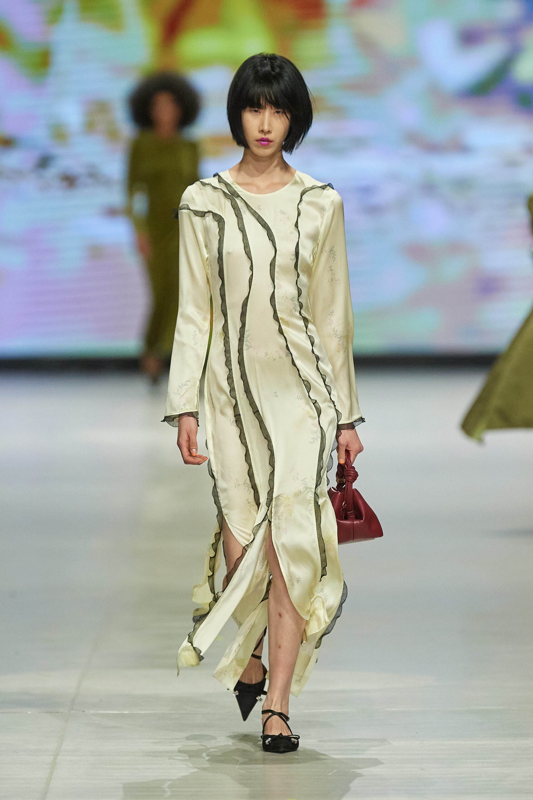 A fitted cream silk long-sleeve dress with a V-neckline and asymmetric slit detail.